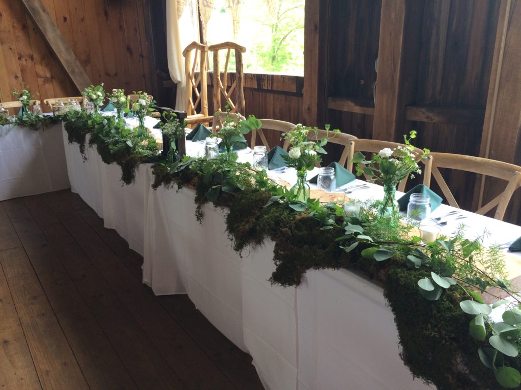 A moss-covered head table created by the Garden by the Gate Floral Design at Rivercrest Farm